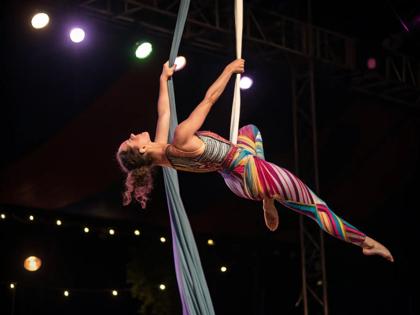 A dynamic image of an acrobat suspended in mid-air during a performance, showcasing the skill and artistry involved in MAISON DE LA's acrobatic programs.